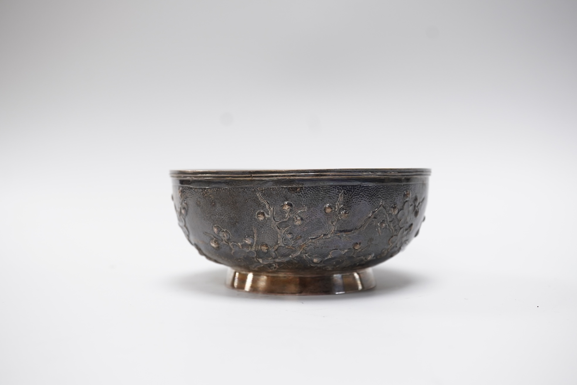 A late 19th/early 20th century Chinese Export white metal bowl, by Wang Hing, Hong Kong, embossed with blossoming prunus branches, diameter 10.6cm, 113 grams.